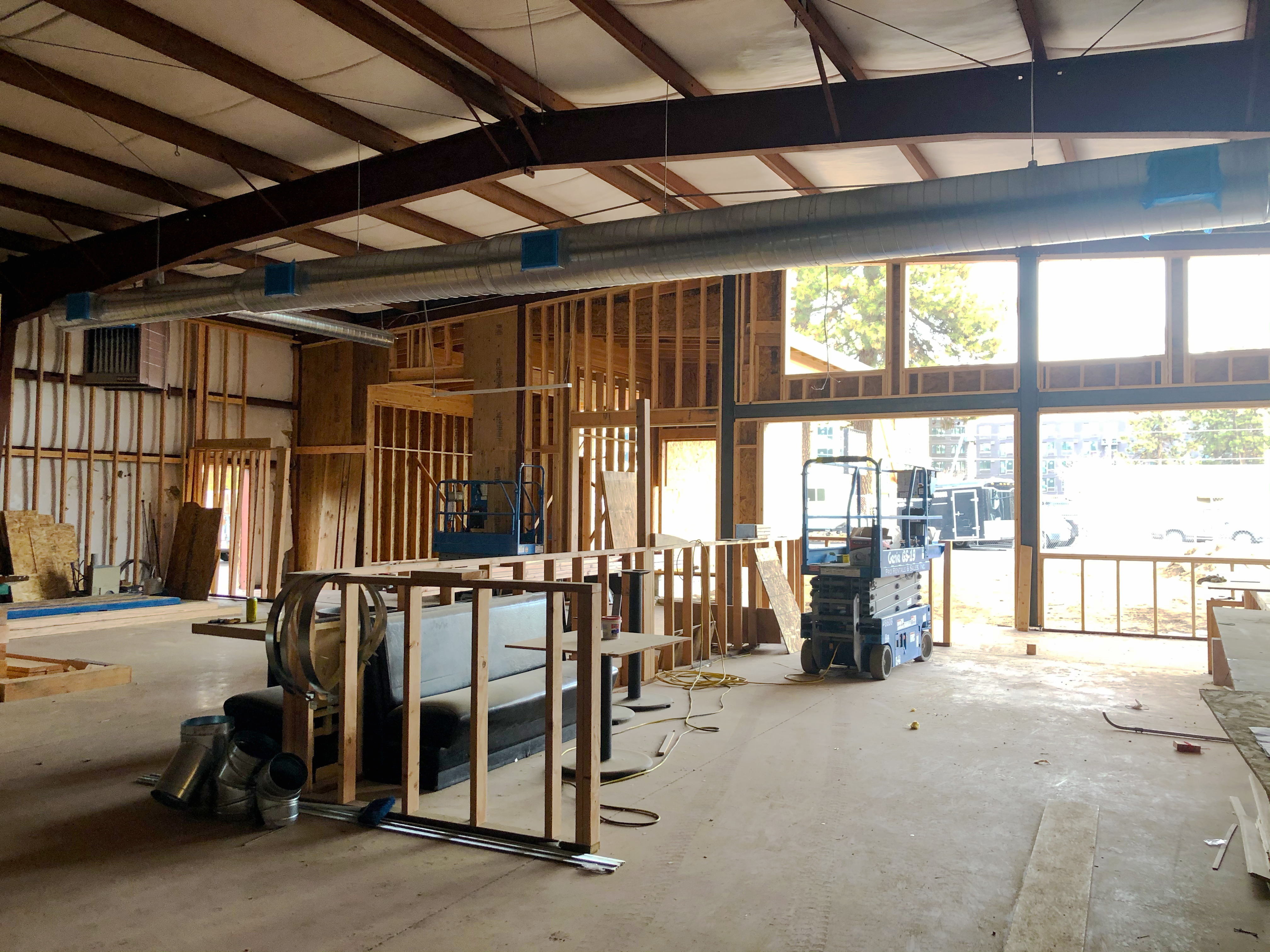 Looking out to the street through the front of the building, still under construction, exposed roof beams and air ducts can be seen along with the wall studs